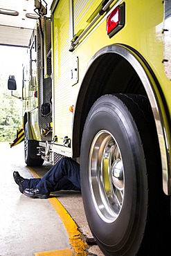 Chinese fireman laying underneath fire truck