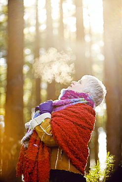 Older Caucasian woman breathing steam outdoors