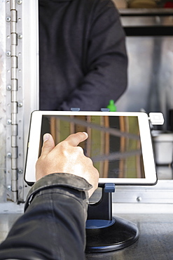 Man paying at food cart using digital tablet