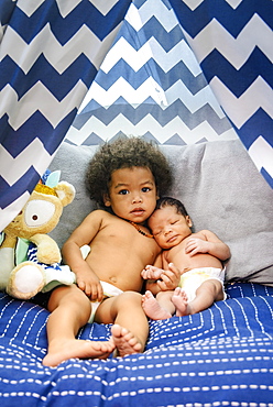 Mixed Race baby boys cuddling on bed