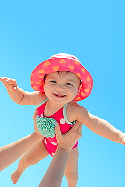 Woman holding baby girl against blue sky