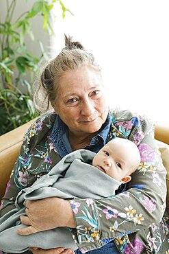 Portrait of smiling grandmother holding newborn grandson (0-1 months)