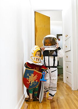 Toddler boy (2-3) in knight costume and girl (2-3) in astronaut costume playing at home