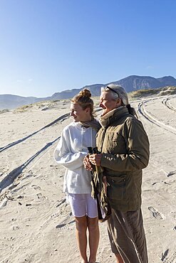 South Africa, Hermanus, Teenage girl (16-17) with grandmother walking on sand dune