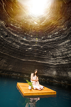 Portrait of woman sitting on floating dock near rocky coast