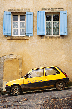 Yellow postal delivery vehicle parked outside a townhouse