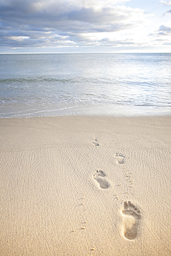 Footprints in sand and calm sea