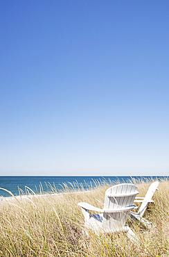 Adirondack chairs facing beach and ocean