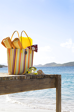 Beach bag with accessories on tropical beach