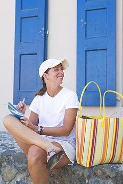 Smiling woman on vacation writing postcard