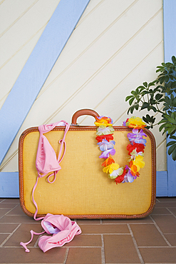 Vintage suitcase with pink bikini and floral garland