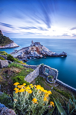 Flowers and blue sea frame the old castle and church at dusk, Portovenere, UNESCO World Heritage Site, La Spezia Province, Liguria, Italy, Europe