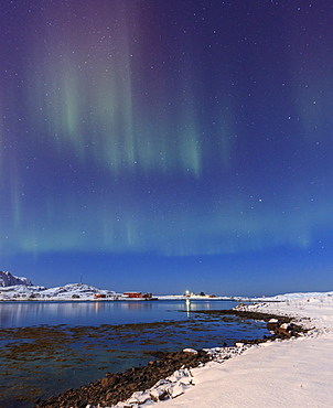 Northern lights (Aurora Borealis) on the snowy peaks reflected in the cold sea, Volanstinden, Fredvang, Lofoten Islands, Northern Norway, Scandinavia, Europe