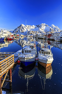 Boats docked in the calm waters of the port of Henningsvaer with the Norwegian Alps in the background, Lofoten Islands, Arctic, Norway, Scandinavia, Europe