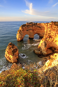 Sunrise on cliffs framed by turquoise water of the ocean, Praia da Marinha, Caramujeira, Lagoa Municipality, Algarve, Portugal, Europe