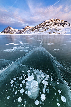 Ice bubbles frame the snowy peaks reflected in Lago Bianco, Bernina Pass, canton of Graubunden, Engadine, Switzerland, Europe