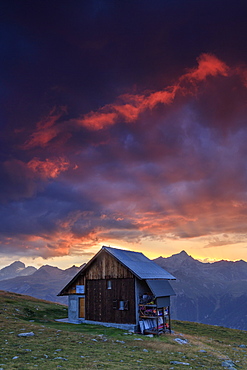 Wooden hut under fiery sky and clouds at sunset, Muottas Muragl, St. Moritz, Canton of Graubunden, Engadine, Switzerland, Europe