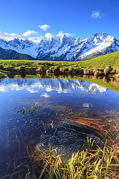 Snowy peaks and blue sky reflected in water at dawn, Tombal, Soglio, Bregaglia Valley, canton of Graubunden, Switzerland, Europe