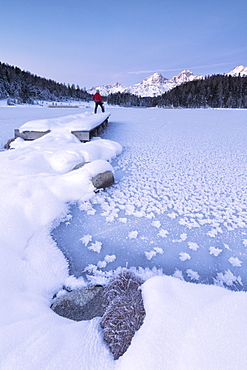 Man standing on the shore of frozen lake, Lej da Staz, St. Moritz, Engadine, Canton of Graubunden (Grisons), Switzerland, Europe