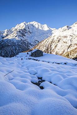 Stone hut at the foot of the snowy Monte Vazzeda, Alpe dell'Oro, Valmalenco, Valtellina, Sondrio province, Lombardy, Italy, Europe