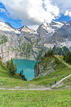 High angle view of two hikers walking on path above Oeschinensee lake, Bernese Oberland, Kandersteg, Canton of Bern, Switzerland, Europe