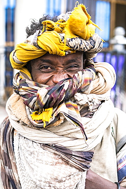 Portrait of young man with headwrap smiling at camera, Bati, Amhara Region, Oromia, Ethiopia, Africa