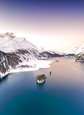 Aerial by drone of Lake Sils surrounded by snowy peaks during a winter sunrise, Engadine, canton of Graubunden, Switzerland, Europe