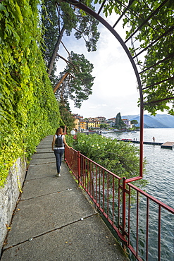 Woman walking on famous lovers' promenade on lakeside of Varenna, Lake Como, Lecco province, Lombardy, Italian Lakes, Italy, Europe