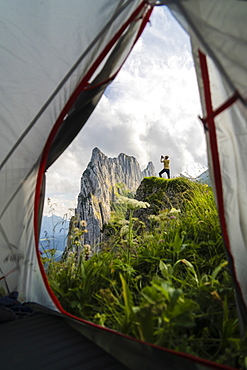 Man on rocks photographing Saxer Lucke mountain with smartphone seen from hiking tent, Appenzell Canton, Switzerland, Europe