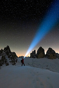 Hiker with head torch admiring stars on Monte Paterno and Tre Cime di Lavaredo, Sesto Dolomites, South Tyrol, Italy, Europe