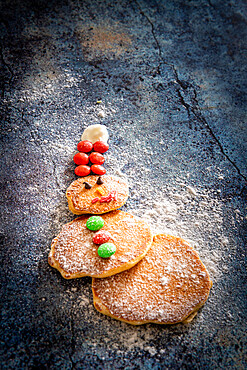 Home made pancakes in shape of snowman decorated with sugar buttons on table background at Christmas time, Italy, Europe