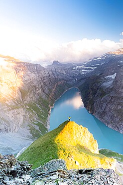 Aerial view of cheerful man with outstretched arms admiring lake Limmernsee at sunset, Canton of Glarus, Switzerland, Europe