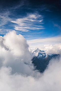 Sunlight over Weisshorn peak emerging from a sea of clouds, canton of Valais, Switzerland, Europe