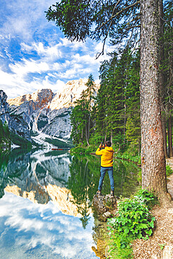 Hiker man photographing Lake Braies (Pragser Wildsee) with smartphone at sunrise, Dolomites, South Tyrol, Italy, Europe