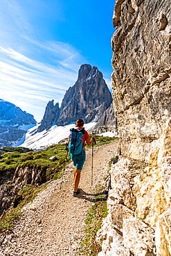 Backpacker woman with hiking poles enjoying the view to Croda Dei Toni from path, Sesto Dolomites, South Tyrol, Italy, Europe