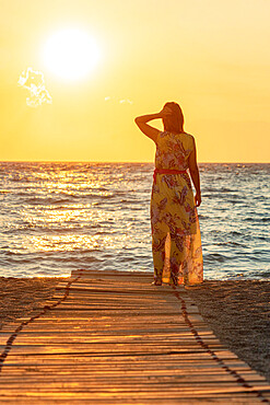 Charming woman contemplating the sea at sunset standing on Matala beach, Crete, Greek Islands, Greece, Europe