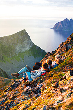 Young Scandinavian women enjoying sunset relaxing together on rocks, Senja island, Troms county, Norway, Scandinavia, Europe