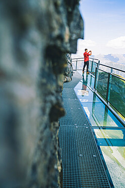 Man photographing mountains with smartphone from the Thrill Walk panoramic glass walkway, Murren Birg, Bern canton, Switzerland, Europe