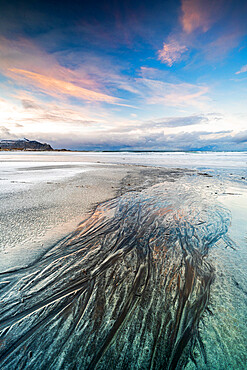 Sunset over the black sand of Skagsanden beach covered with ice in winter, Flakstad, Nordland county, Lofoten Islands, Norway, Scandinavia, Europe