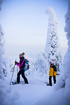 Cheerful mother with son snowshoeing in the frozen forest, Oulanka National Park, Ruka Kuusamo, Lapland, Finland