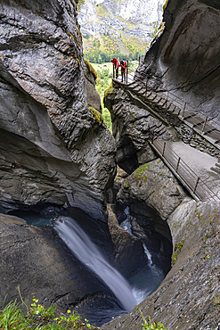 Two hikers photographing Trummelbach Falls from path inside majestic rock canyons, Lauterbrunnen, canton of Bern, Switzerland, Europe