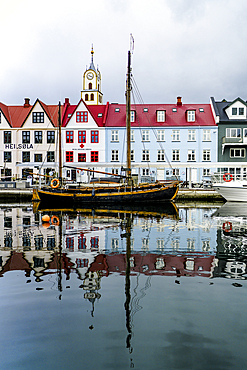 Old wooden ship and colorful buildings reflected in water in Torshavn harbour, Streymoy Island, Faroe Islands, Denmark, Europe