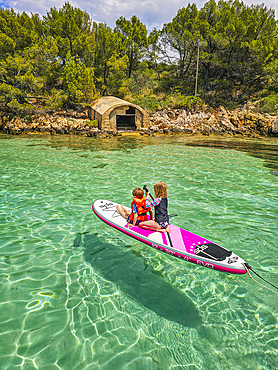 Kids on a SUP in the turquoise waters of the Formentor Peninsula, Mallorca, Balearic islands, Spain, Mediterranean, Europe