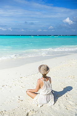 Woman sitting on a white sand beach enjoying the turquoise water, Sun Island Resort, Nalaguraidhoo island, Ari atoll, Maldives, Indian Ocean, Asia