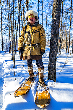 Traditional dressed Evenki hunter with snow shoes before a traditional Evenki Yurt in Tura, Krasnoyarsk Krai, Evenki state, Russia