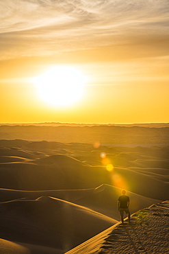 Man enjoying the sunset in the giant sand dunes of the Sahara Desert, Timimoun, western Algeria, North Africa, Africa