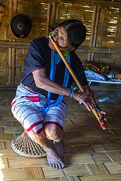 Chin woman with spiderweb tattoo blowing a flute with her nose, Kanpelet, Chin state, Myanmar (Burma), Asia