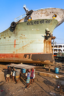 Men carrying a very heavy metal plate to the river, shipwreck cemetery (ship breaking yard), Port of Dhaka, Bangladesh, Asia