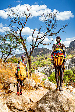 Traditional dressed young girls from the Laarim tribe standing on a rock, Boya Hills, Eastern Equatoria, South Sudan, Africa