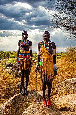 Traditional dressed young girls from the Laarim tribe standing on a rock, Boya Hills, Eastern Equatoria, South Sudan, Africa